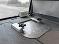 A metal mounting plate with two black knobs and a white electrical outlet is positioned on a flat surface inside a vehicle