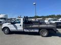 A white 2016 Ford F-350 SD flatbed truck positioned sideways with a black flatbed and metal railing