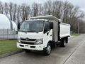 A white 2014 Hino 195 truck with a flatbed and closed cargo area in the back parked on a concrete surface