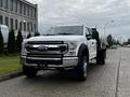 2021 Ford F-550 chassis cab with a white exterior and chrome grille positioned on a urban street