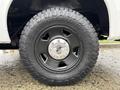 Close-up of a black wheel of a 2008 Ford F-250 SD featuring a shiny silver hubcap and rugged Toyo Tires with deep treads