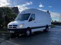 A 2008 Dodge Sprinter Van with a white exterior and a sleek design parked on a road