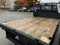 A 2020 Ford F-350 SD with a flatbed featuring a wooden surface and a metal frame with a mesh back