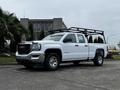 A white 2018 GMC Sierra 1500 with a rack on the bed parked on a concrete surface