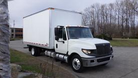 A 2012 International TerraStar truck with a white box cargo area and chrome accents parked with the cab facing forward