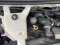 Close-up of the engine compartment of a 2018 Chevrolet Express showing the coolant reservoir and various hoses and fittings