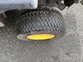 A close-up view of a tire from a 2014 John Deere 1585 Terrain Cut with a sturdy tread pattern and a yellow rim