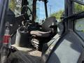 Interior of a 2011 John Deere 310SJ backhoe loader showing the operator's seat control panel and steering wheel
