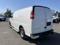 A white 2016 GMC Savana cargo van is parked with its rear view visible showcasing its simple design and sliding side door