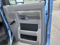 Interior door panel of a 2010 Ford Econoline featuring a gray handle control a storage compartment and textured surface design