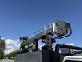 A 2023 Ford F-550 utility truck with a raised aerial lift equipped with a mechanical arm for maintenance tasks