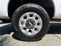 Close-up of a silver wheel and black tire of a 2014 Ford F-250 SD showcasing the tread pattern and wheel design