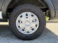 Close-up of a wheel and tire from a 2022 Ford Transit featuring a silver five-spoke rim and rugged all-terrain tire tread