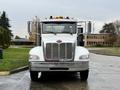 Front view of a white 2020 Peterbilt 330 truck featuring chrome detailing and a prominent grille with auxiliary lights on the roof