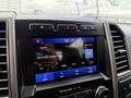 The dashboard display of a 2019 Ford F-150 showing the audio source settings with a radio station and song information
