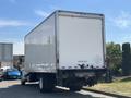 A 2015 Freightliner M2 106 box truck with a white cargo area and rear door visible, parked at an angle with no visible markings on the truck surface