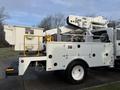 A white 2013 International Durastar 4300 bucket truck with an elevated boom and a cream-colored utility body designed for maintenance work