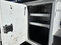 An open compartment of a 2016 Ford F-550 displaying two metal shelves inside the white enclosure