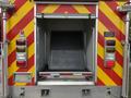 The back of a 2007 Ford F-550 ambulance with a ramp and red and yellow reflective striping indicating emergency vehicle status