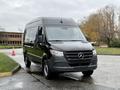 A 2022 Mercedes-Benz Sprinter van in black with a sleek design and prominent front grille parked on a wet surface