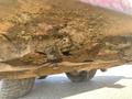 Underside view of a 2010 Kubota F3680 showing a dirty metal chassis with accumulated debris and grass around the blades and components