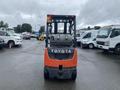 A 2011 Toyota 028FG15 forklift viewed from the rear showing its distinctive orange body and dual tank setup
