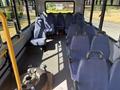 Interior of a 2017 Chevrolet Express bus with rows of blue seats and a spare tire on the floor near the back