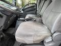 Interior of a 2015 Isuzu NPR HD showing a gray driver's seat and passenger seat with fabric upholstery and a simple dashboard design