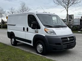 A white 2018 RAM Promaster van with a boxy shape and sliding side door parked on a street