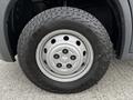 Close-up of a silver wheel with six lugs and a rugged tire marked with the brand name on its sidewall