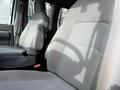 Interior of a 2014 Ford Econoline showing two gray fabric front seats with seat belts and a simple design