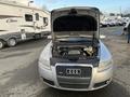 A silver 2006 Audi A6 with the hood raised showcasing the engine compartment