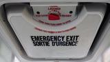 A ceiling-mounted emergency exit door with instructions in English and French indicating how to open it