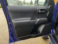 A blue 2022 Toyota Tacoma door panel with a black armrest and control buttons for windows and locks