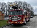 A red 2009 Spartan Gladiator fire truck with a ladder on top and the number E-1 displayed on the front grille