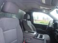 Interior of a 2015 Chevrolet Silverado 1500 showing front seats with fabric upholstery and a center console with cup holders