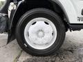 A close-up of a white wheel featuring a five-bolt pattern with a circular center cap and a black tire with a tread pattern designed for durability