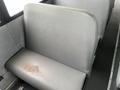 A gray bus seat showing signs of wear and a stain on the cushion