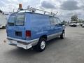 A blue 2009 Ford Econoline van with a roof rack and no visible license plate positioned at an angle