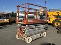 A Skyjack SJ scissor lift with an orange frame and grey platform raised above ground level on wheels