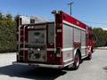 A red 2006 Emergency One Fire Truck with a rear-mounted ladder and various firefighting equipment visible on the back panel