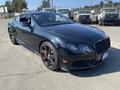 A black 2015 Bentley Continental GT with sleek lines and black rims parked at an outdoor location