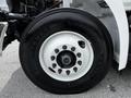 A close-up view of a black tire mounted on a white wheel rim with multiple lug nuts prominently displayed