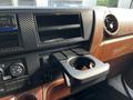 Dashboard of a 2021 Hino 338 showing a black carbon fiber trim cup holder with a space for a drink and various controls and features just below it
