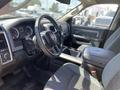 Interior view of a 2015 RAM 1500 showing the steering wheel dashboard and center console with gray upholstery and controls