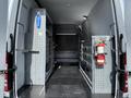 Interior of a 2017 Mercedes-Benz Sprinter with metal shelving units and drawers on both sides a fire extinguisher mounted on one side