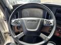 The steering wheel of a 2022 Freightliner Cascadia with buttons for audio and cruise control integrated into the design
