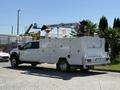A 2024 Ford F-550 Super Duty service truck with a white body and a crane mounted on top positioned on the bed