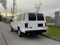 A white 2011 Ford Econoline van parked with tinted windows and chrome wheels