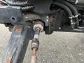 Close-up of the steering mechanism connecting rod of a 2007 New Holland TN70A tractor with visible wear and rust on the components